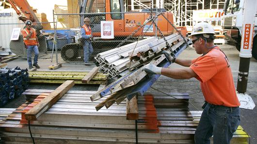 Construction workers move materials at a work site for a new condominium and retail complex in Portland, Oregon.